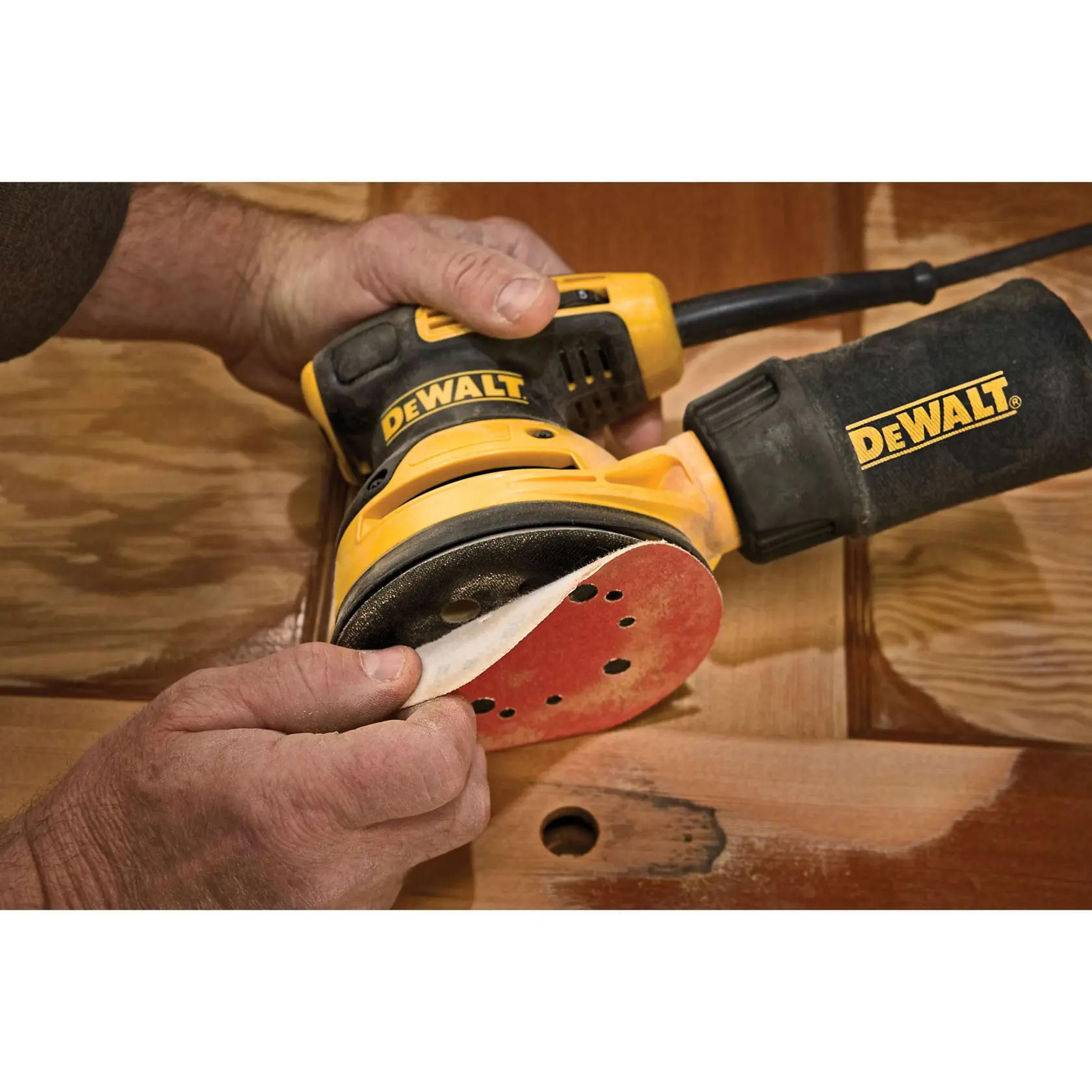 Manufacturer close-up of a sanding disc being aligned with the pad on the DeWalt DWE6423K
